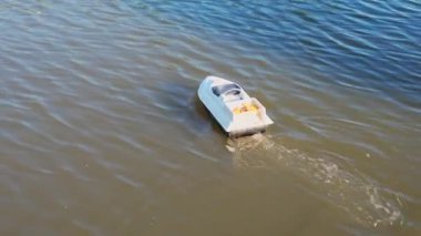 Uzaktan kumandalı oyuncak tekne sakin bir gölde hızla ilerliyor, güneşli bir gün yaratıyor..