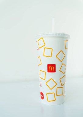 Kyiv, Ukrayna - 23 Mart 2025: Beyaz bir yüzey üzerinde McDonald 's logosu ve sarı kare tasarımı bulunan kamışlı bir McDonald' s kağıt bardağı