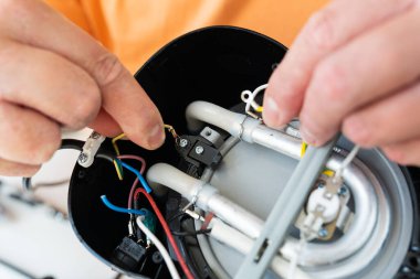 Bir insan, bozuk bir cihazın iç kablosunu ve bileşenlerini dikkatlice onarır..