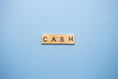 Açık mavi arkaplanda 'CASH' kelimesini heceleyen tahta bloklar.