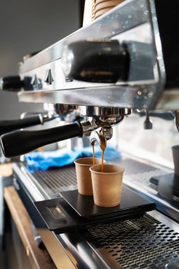 Espresso makinesi iki tek kullanımlık fincana mükemmel ölçülerde kahve doldurur..