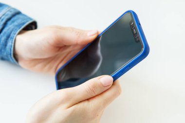 Kız elinde bir akıllı telefon tutuyordu. Çevrimiçi çalışma kavramı, serbest çalışma, yazışma, sohbet