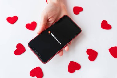 Beyaz arka planda kırmızı kalplerle çevrili yeni bir mesaj bildirilmiş akıllı telefonu tutan kız