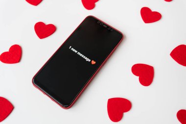 Kırmızı kalplerle çevrili, beyaz arka planda 1 yeni ileti bildirimi gösteren bir akıllı telefon