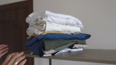 Raftan düzgün katlanmış giysiler alınıyor. Ev işleri..