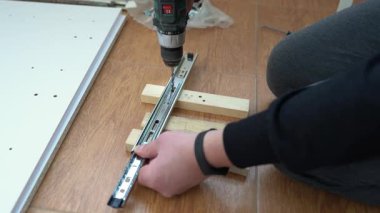 Adam matkap ve çekmeceyle mobilya monte ediyor. Ev tadilatı, DIY projesi. Kendin yap..
