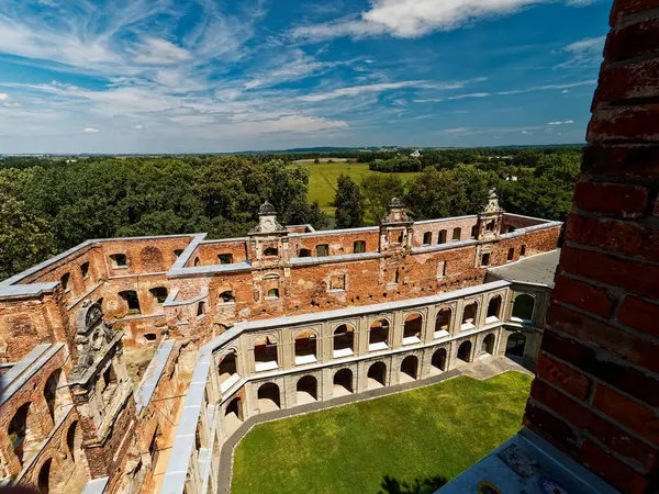 Polonya 'nın Tworkw kentindeki sarayın kalıntıları eski çağın bir kanıtı olarak duruyor. Bu hava manzarası, bir zamanların büyük yapısının geniş zeminini ve karmaşık tuğlalarını sergiliyor. Çevreleyen yeşillik ve uzak ufuk.