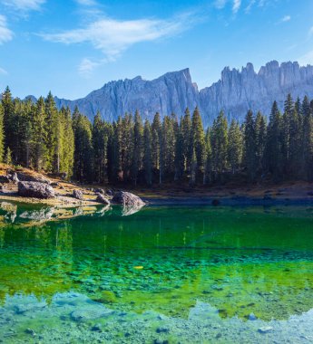 Sunny colorful autumn alpine Dolomites mountain scene, Sudtirol, Italy. Karersee or Lago di Carezza view. Picturesque traveling, seasonal, nature and countryside beauty concept scene.