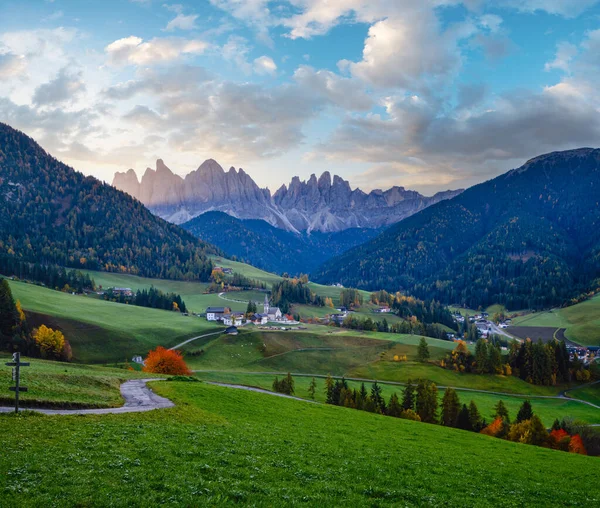 Autumn daybreak Santa Magdalena famous Italy Dolomites village view in front of the Geisler or Odle Dolomites Group mountain rocks. Picturesque traveling and countryside beauty concept background.