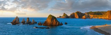 Atlantic ocean coastline landscape in red sunset sunrays. Beautiful Gueirua beach with sharp islets, Asturias, Spain.