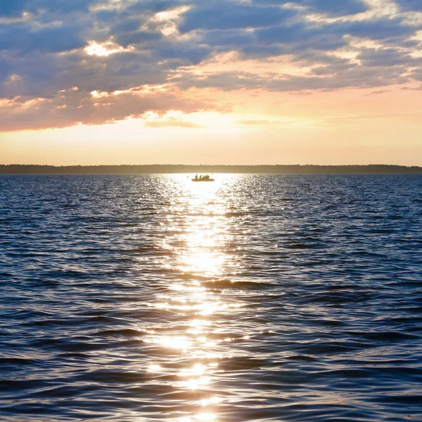 夏の湖の表面の日没 太陽のトラックと漁船 — ストック写真
