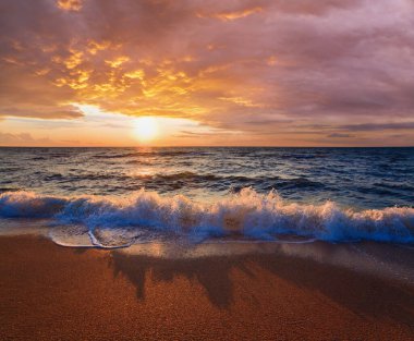 Deniz gün batımı dalgaları kumlu sahil şeridinde dalgalanır
