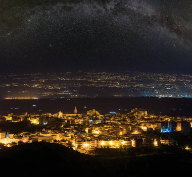 Gece Lentini kasabası dağ yolundan denize ve Etna volkanı (Siracusa, Sicilya, İtalya) ve Samanyolu yıldızlarından yukarıya doğru yol alır..