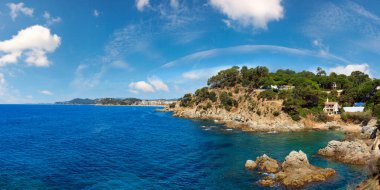 Yaz denizi kayalık kıyı manzarası (Lloret de Mar kasabası yakınlarında, Katalonya, İspanya). İnsanlar tanınmaz halde..