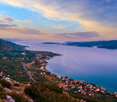 Deniz batımı, Hırvat adaları ve deniz kıyısındaki Viganj köyü (Peljeac yarımadası, Hırvatistan) ve uzak Korcula köyü ve adası. 