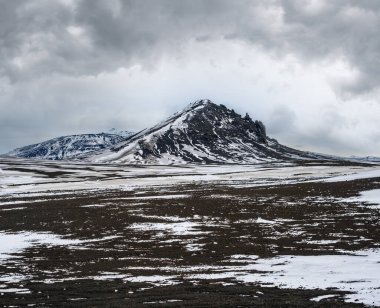 Sonbaharda İzlanda 'da kar altında renkli Landmannalaugar dağları. Önplanda volkanik kumdan oluşan lav alanları.