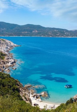Akuamarin şeffaf su ve kayalık sahil kumlu plaj tekne ile yaz deniz sahne. Kıyıdan (Sithonia, Halkidikya, Yunanistan görüntülemek).