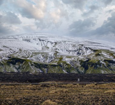 Güney İzlanda 'da mevsim değişiyor. Sonbaharda kar altında renkli Landmannalaugar dağları. Önplanda volkanik kumdan oluşan lav alanları.