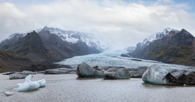 Buzul dili Vatnajokull buzulundan ya da İzlanda 'daki Oraefajokull volkanı yakınlarındaki Vatna Buzulu' ndan kayar. Buzul gölü, buz blokları ve etrafındaki dağlarla.