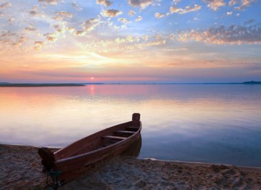gün batımı ve eski ahşap balıkçı teknesi yakınındaki yaz göl kıyısı (svityaz, Ukrayna)