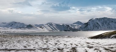İzlanda dağlarında mevsim değişimi. Sonbaharda kar altında renkli Landmannalaugar dağları. Dağın eteğindeki Frostastadavatn Gölü.
