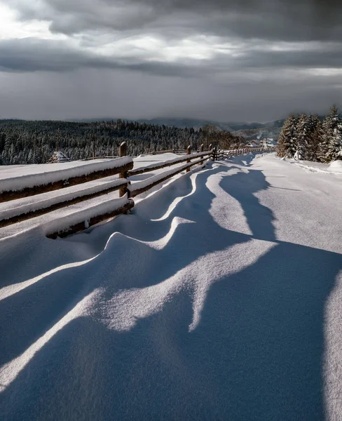 风景如画的影子在雪地上从木栅栏上飘扬 高山冬季小村子郊外 雪地小径 冷杉林 分辨率高 场深度大的图像 — 图库照片
