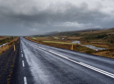 İzlanda 'da otomobil gezisi sırasında otoyol ve dağ manzarası. Manzaralı İzlanda manzarası: dağlık alanlar, bulutlar, buzullar, şelaleler