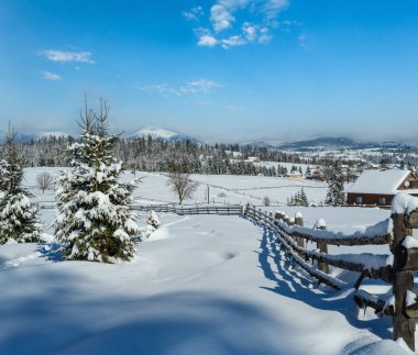 Kış uzak dağlık dağ köyü, kırsal tepeler, ağaçlar ve tarım arazileri.