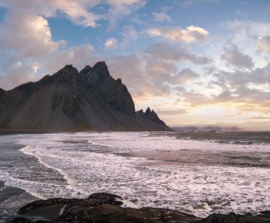 Sunrise Stoksnes Cape Deniz Sahili ve Vestrahorn Dağı ve okyanus sörfü. İnanılmaz doğa manzarası, popüler seyahat merkezi..