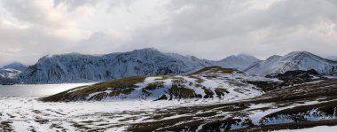 İzlanda dağlarında mevsim değişimi. Sonbaharda kar altında renkli Landmannalaugar dağları. Dağın eteğindeki Frostastadavatn Gölü.