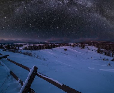 Gece kırsal tepeler, koruluklar ve kışın uzak dağlık dağ köyündeki tarım alanları ve yukarıda Samanyolu ile yıldızlı gökyüzü. Ukrayna, Voronenko.