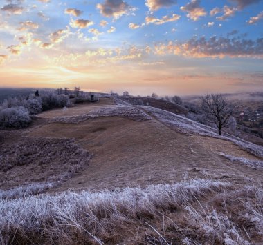 Kış geliyor. Sonbaharın sonlarına doğru, çimlerde, ağaçlarda, yamaçlarda kırağı olan, gündoğumu manzarası. Bulutlu gökyüzünden barışçıl güneş ışınları. Ukrayna, Karpat Dağları.