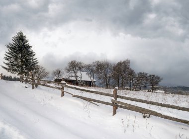 Kış uzak dağlık dağ köyü, kırsal tepeler, ağaçlar ve tarım arazileri..