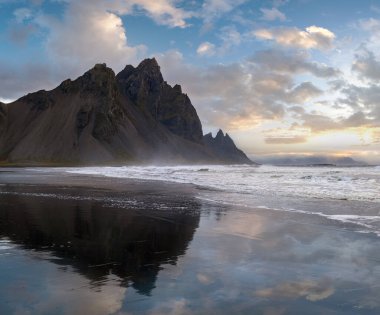 Gündoğumu Stoksnes Cape Deniz Sahili ve Vestrahorn Dağı Islak siyah volkanik kum yüzeyi, İzlanda. İnanılmaz doğa manzarası, popüler seyahat merkezi..