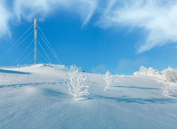 Ağaçlar, iletişim kulesi ve snowdrifts dağın tepesinde mavi gökyüzü arka plan (Karpatlar, Ukrayna üzerinde buzlanma güzel kış in rime'ı)