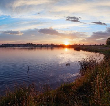 Göl yaz gün batımı manzaralı güneş yansıma ve araba ile kıyısında. Tüm insanlar tanınmaz