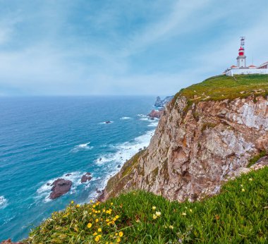 Çiçek açması Cape Roca (Cabo da Roca) çiçek ve deniz feneri ile yaz. Atlantik Okyanusu kıyısında görünümünde bulutlu hava, Portekiz.