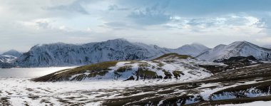 İzlanda dağlarında mevsim değişimi. Sonbaharda kar altında renkli Landmannalaugar dağları. Dağın eteğindeki Frostastadavatn Gölü.