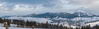 Voronenko, Carpathian, Ukrayna çevresindeki küçük Alp köyü ve kışın ilk gün doğumunda karlı dağlar..