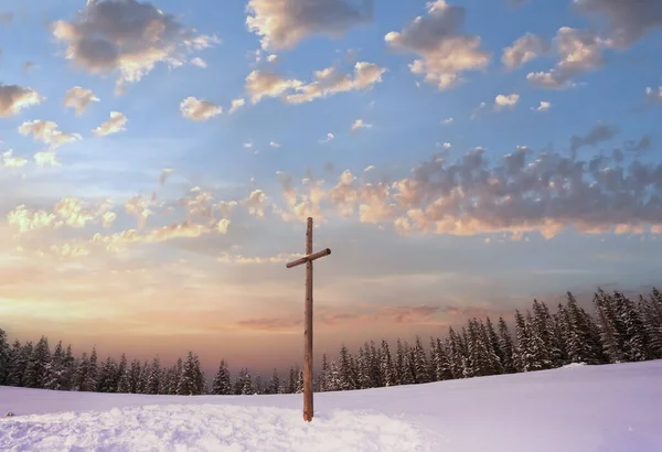 Winter snowy fir trees on mountainside on overcast sky background and wooden cross in front (Carpathians, Ukraine)