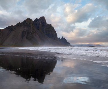 Gündoğumu Stoksnes Cape Deniz Sahili ve Vestrahorn Dağı Islak siyah volkanik kum yüzeyi, İzlanda. İnanılmaz doğa manzarası, popüler seyahat merkezi..