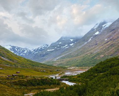 Nehir ve kırsal evler ile yaz bulutlu dağ manzara (Norveç).