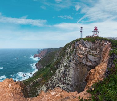 Çiçek açması Cape Roca (Cabo da Roca) çiçek ve deniz feneri ile yaz. Atlantik Okyanusu kıyısında görünümünde bulutlu hava, Portekiz.