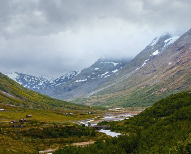 Nehir ve kırsal evler ile yaz bulutlu dağ manzara (Norveç).