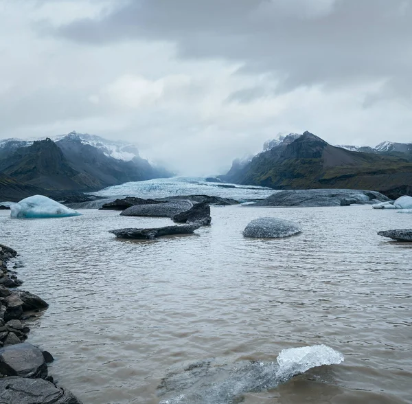 冰川舌从冰岛冰川下Rfajkull火山附近的Vatnajkull冰盖或Vatna冰川滑出 有冰块和周围山脉的冰川泻湖 — 图库照片