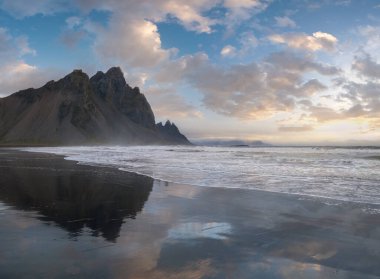 Gündoğumu Stoksnes Cape Deniz Sahili ve Vestrahorn Dağı Islak siyah volkanik kum yüzeyi, İzlanda. İnanılmaz doğa manzarası, popüler seyahat merkezi..