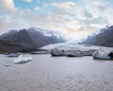 Buzul dili Vatnajkull buzulundan ya da İzlanda 'nın buzul altı volkanı yakınlarındaki Vatna Buzulu' ndan kayar. Buzul gölü, buz blokları ve etrafındaki dağlarla. 