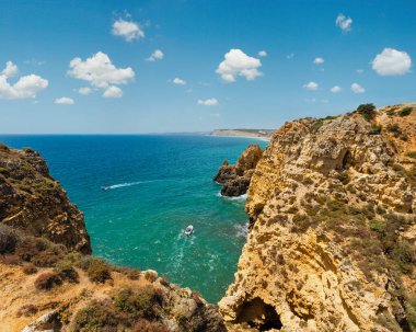 Atlantik Okyanusu yaz kayalık sahil şeridi görünümü (Ponta da Piedade, Lagos, Algarve, Portekiz). Motorbot tanınmayan insanlar.