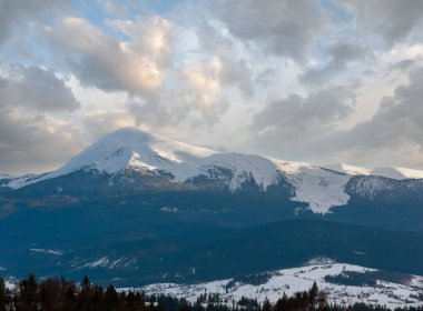 Evening twilight winter cloudy day snow covered alp mountain ridge (Ukraine, Carpathian Mountains, Chornohora Range - Petros and other mounts, scenery view from Yablunytsia pass). clipart