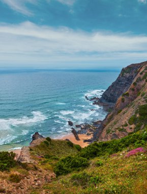 Sandy beach taşlı sırtlar ile hava görünümü yaz Atlantik kayalık kenarı (Costa Vicentina, Algarve, Portekiz) bulutlu. Ve okyanus sörf dalgalar.